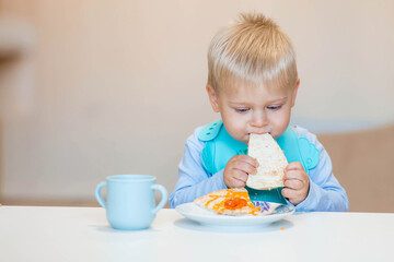 Unhealthy food for children. Eating. A cute 2-year-old kid eats pizza for lunch. Fast food. Family and children.