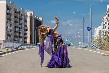 Sexy beautiful woman in a purple costume dances on the street