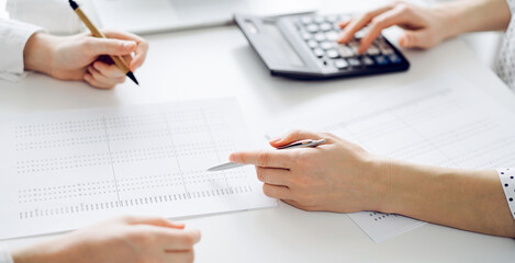 Accountant using a calculator and laptop computer for counting taxes with a client or a colleague...