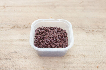 Meses chocolate 4. Chocolate Meses in a plastic container on a wooden background