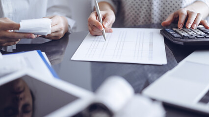 Woman accountant using a calculator and laptop computer while counting taxes with a client or...
