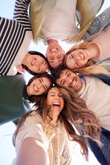 Vertical. Selfie portrait from below of diverse generation z group friends posing smiling in circle...