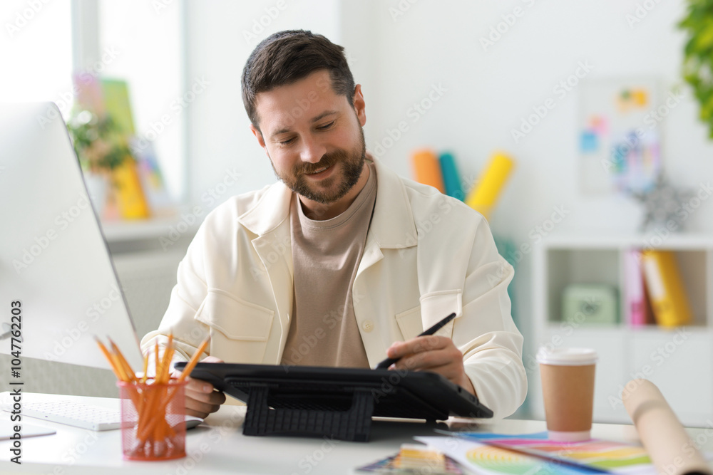 Poster designer working with tablet at table in office
