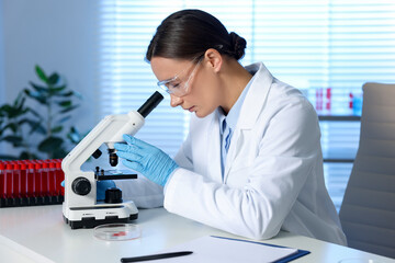 Laboratory testing. Doctor working with microscope at table indoors