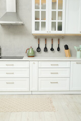 Stylish soft rug on wooden floor in kitchen