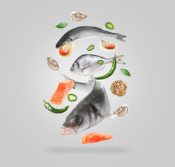 Different sea food in air on light grey background