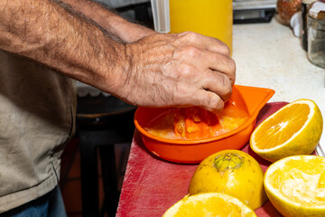 Latin man hands squeezing orange juice for his family. Farm oranges, Colombian home.