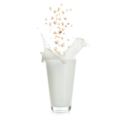 Soy beans falling into glass of plant milk on white background