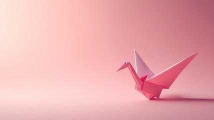Fototapeta premium Pink origami crane on soft pink background, showcasing delicate craftsmanship