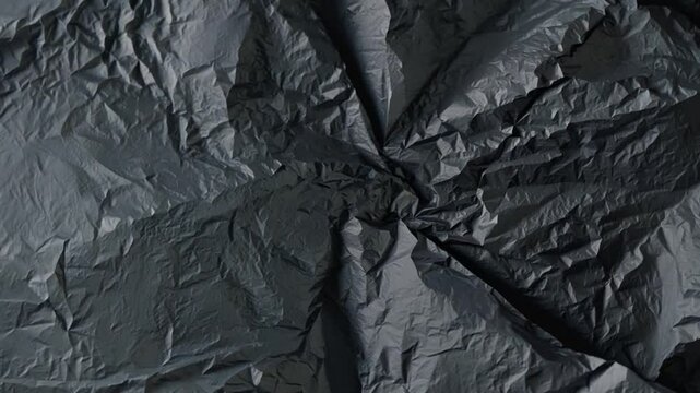 A deep black textured surface created from crumpled paper reveals intricate creases and shadows, perfect for creative projects or a striking backdrop.