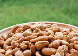 Roasted cashews in bowl on background.