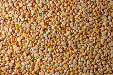 Uncooked Polished Split Peas Background. A Culinary Canvas of Dry Yellow Peas, Creating a Lively and Textured Background for Gourmet Cooking. Scattered Raw Polished Peas. Healthy Eating Ingredients