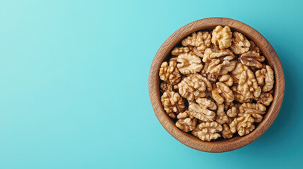 Obraz premium A wooden bowl filled with walnuts on a light blue background.