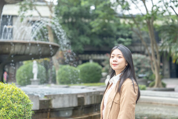 A long-haired Taiwanese woman in her 20s wearing a beige trench coat spends her winter afternoon...