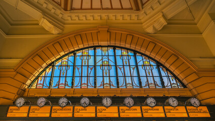 Inside the main entrance of Flinders Street Station in Melbourne, Australia showing the  impressive large stained glass window, clocks, and architectural details.