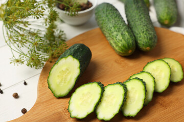 Fresh whole and cut cucumbers with spices on white wooden table, closeup