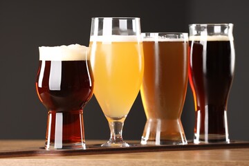 Glasses with different types of beer on wooden table indoors, closeup