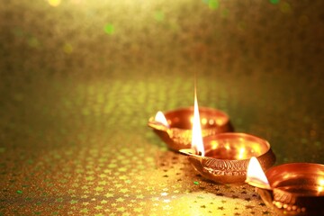 Diwali celebration. Diya lamps on golden background. Space for text