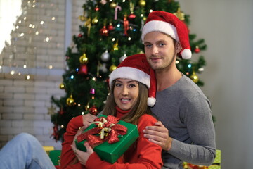 Caucasian lover, couple man and woman open gift box to celebrate Christmas together with decorated Christmas tree. Merry Christmas and Happy Holidays. Christmas holiday celebration and happy new year.