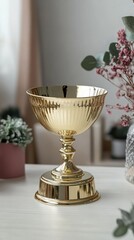 Gold-plated decorative bowl with a pedestal on a white table.