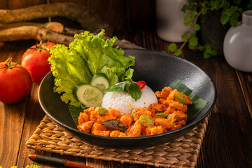 A delicious traditional Indonesian dish of rice with sambal goreng pete and potatoes, served on a black plate.
