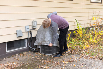 Man covering ac unit. Air conditioner protective cover
