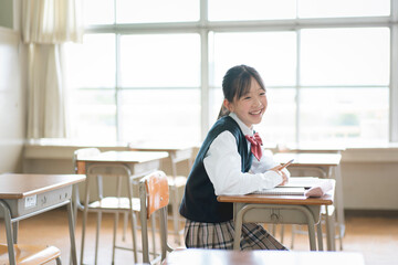 教室の中で座っている笑顔の女子中学生