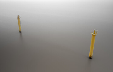 Two yellow lighthouses on calm water. Long exposure.