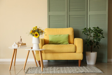 Armchair and vase with wild flowers on coffee table in living room