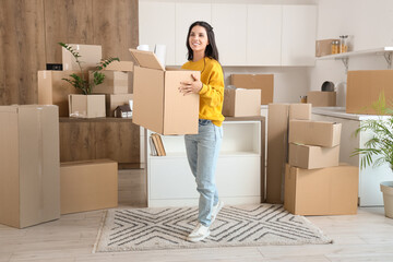 Beautiful woman carrying box in kitchen on moving day