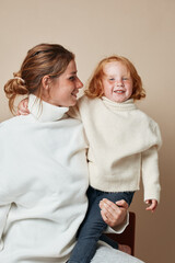 Mother and daughter embracing in white turtleneck sweater family, love, and warmth in winter fashion portrait