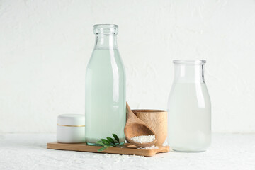 Bottles of natural rice water, grains and cream on light background