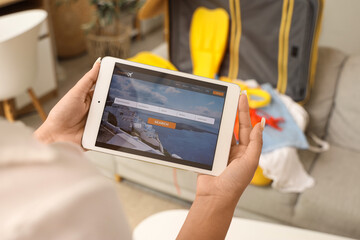 Female tourist with tablet computer at home, closeup. Concept of online booking