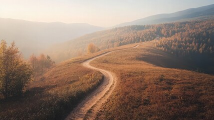 A winding dirt road leads through a grassy hilltop in the mountains.