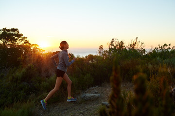 Woman, trail and running in forest at sunrise for fitness athlete in exercise, training and workout. Morning, nature and female runner in outdoor sports for practice for wellness and health in woods