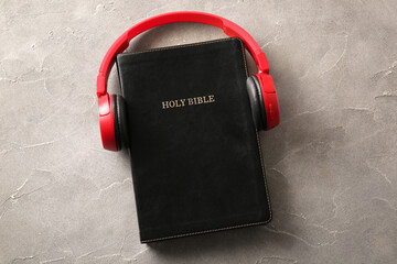 Holy Bible with modern headphones on grunge background