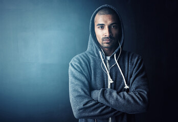 Man, arms crossed and earphones in studio for training with portrait, workout and hoodie by dark background. Person, music and mock up space to start exercise, pride and fitness routine in Mexico