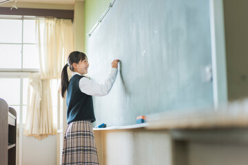 黒板に書いている日本人の女子中学生