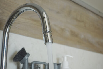 Fresh water is flowing gracefully from a sleek, shiny chrome faucet in a cozy kitchen setting,