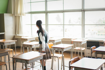 教室の窓の外を見る日本人の女子中学生