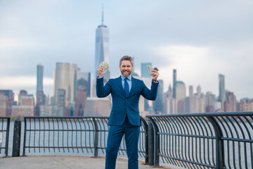 Mature Business man with dollars money. Excited boss director with dollar money on street. Rich business man in suit hold dollar cash. Businessman hold dollars banknotes at city. Dollars cash loan.