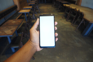 An individual is holding a smartphone within a cozy and inviting cafe environment setting