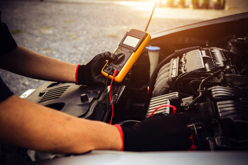 Electrical technician car mechanic use voltmeter to check voltage battery low energy problem for...
