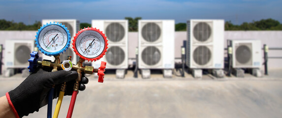 Air Conditioning service technician using measuring manifold gauge checking refrigerant and filling...