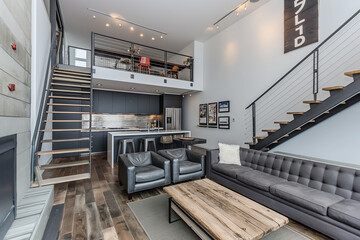 Industrial minimalist open-plan living room with a mix of metal and wood textures, simple black furniture, and a compact kitchen with exposed shelving.
