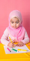 Young Girl in Pink Hijab Drawing with Colored Markers on Yellow Table