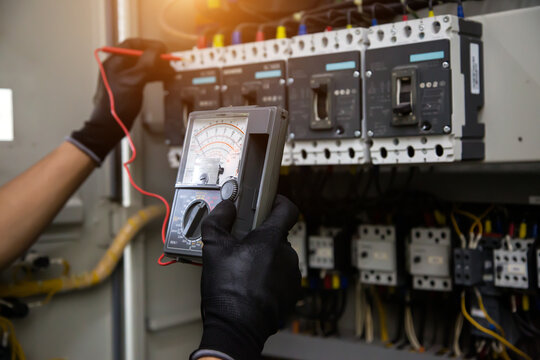 Electrician holding electrical measuring tool meter checking circuit breaker power electricity switchboard for service maintenance and electric cable wiring check for safety concepts.