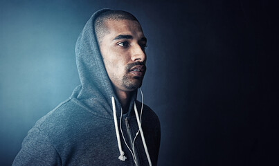 Fototapeta premium Fitness, thinking and man in studio with hoodie, earphones and mockup space at gym workout. Health, wellness and athlete with music app for exercise, inspiration and confidence on dark background