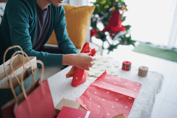 Man wrapping Christmas gift box by decorative colour paper