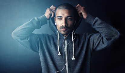 Man, fitness and hoodie in studio for training with thinking, workout and earphones by dark background. Person, music and listen with audio streaming subscription for exercise, routine and health